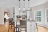 Kitchen with a breakfast bar area, white cabinets, dark stone countertops, backsplash, and recessed lighting