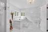 Primary 2nd floor Bathroom with marble tile , jetted tub, separate shower , dual sinks , and a chandelier.