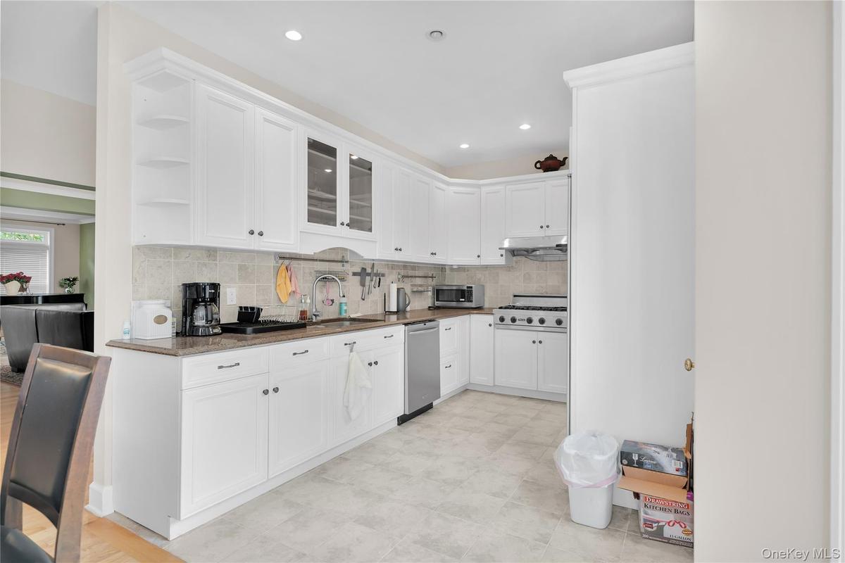 Kitchen featuring open shelves, white cabinetry, glass insert cabinets, backsplash, and recessed lighting