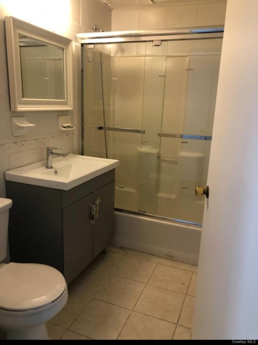 Full bathroom featuring tile patterned floors, vanity, toilet, and bath / shower combo with glass door