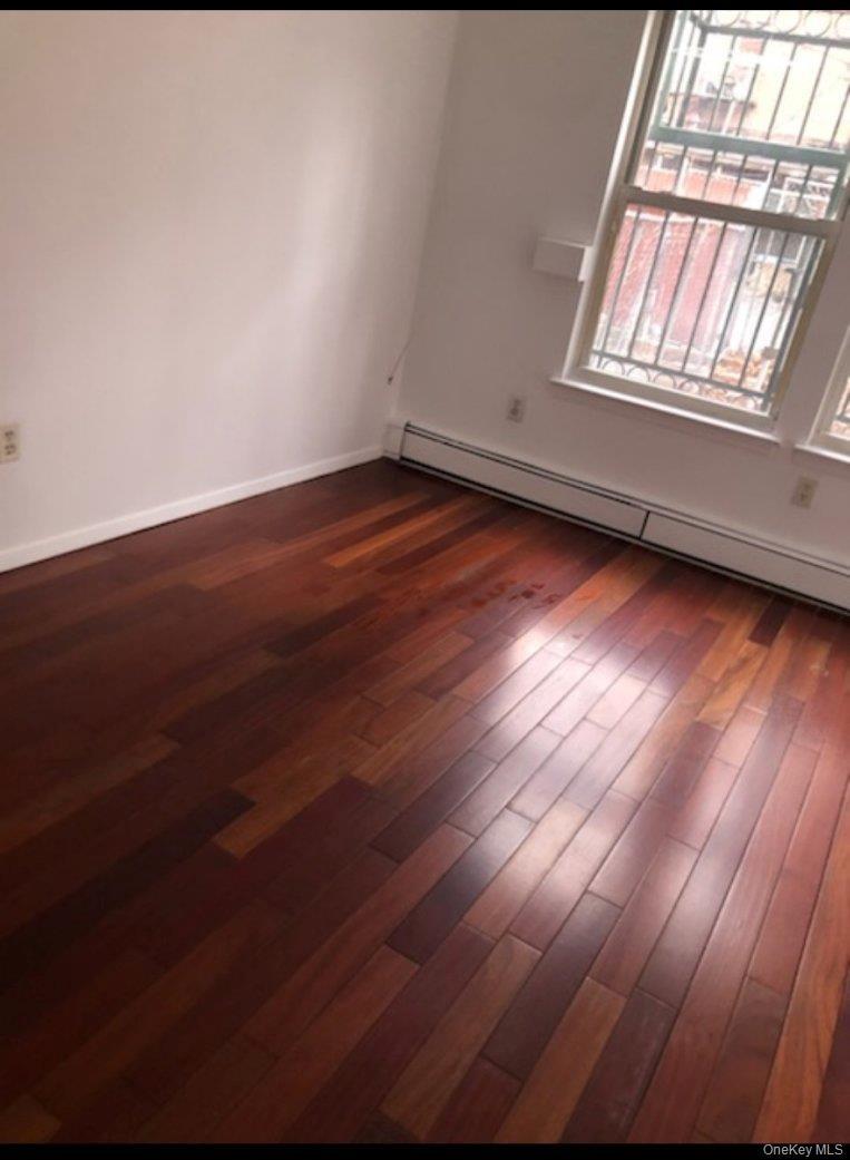 Spare room featuring dark hardwood / wood-style floors and a baseboard radiator