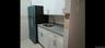 Kitchen featuring white cabinetry, sink, light stone countertops, black fridge, and tile walls