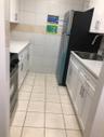 Kitchen with stove, white cabinetry, tile walls, and sink