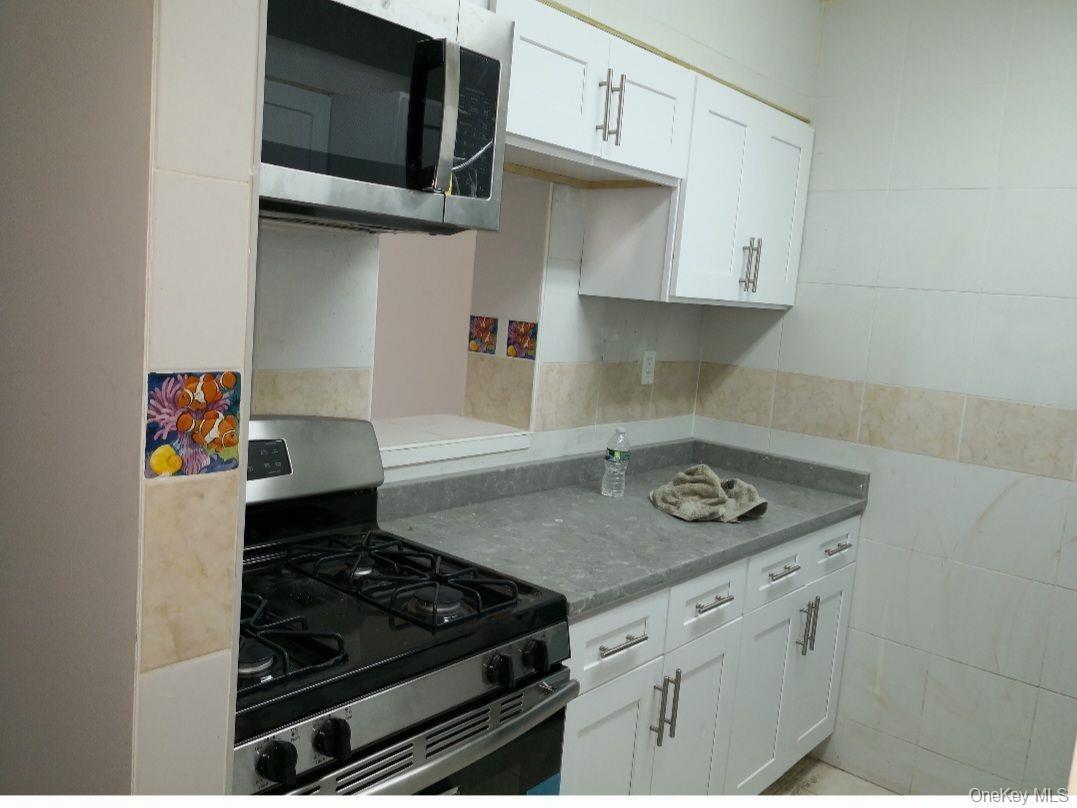 Kitchen with white cabinets, stainless steel appliances, and tile walls