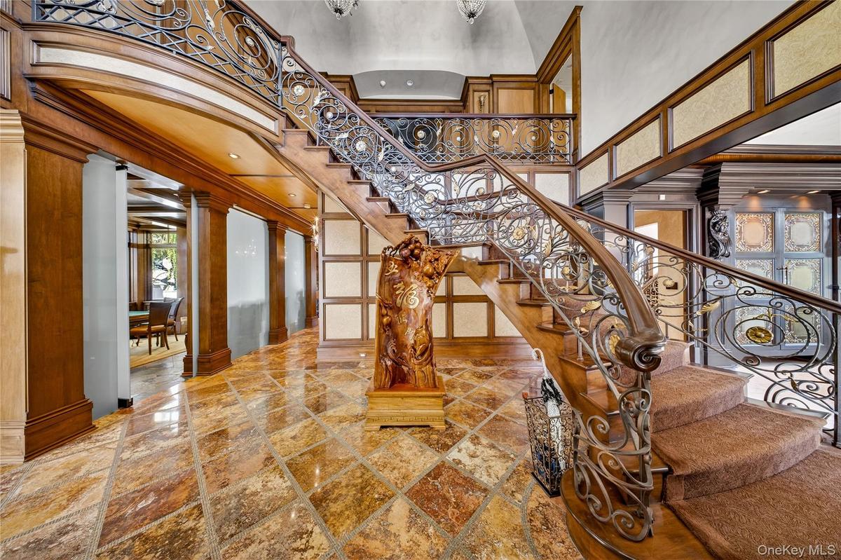 Entryway featuring a grand staircase with ornate wrought iron railings and a carpeted tread