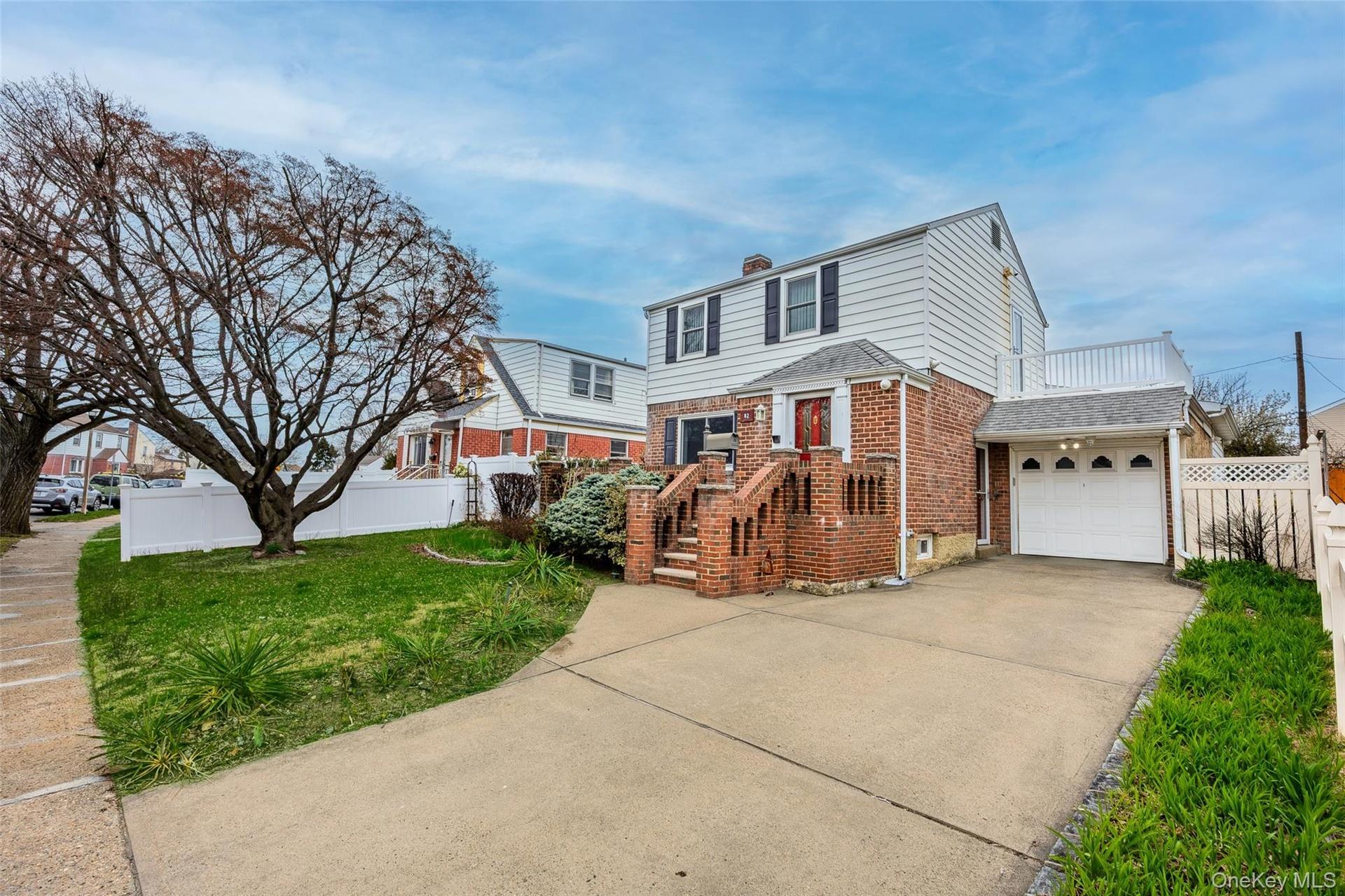 The property features a driveway, an attached garage, and a front lawn with a mature tree