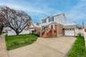 The property features a driveway, an attached garage, and a front lawn with a mature tree