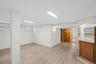 This expansive room features light-toned flooring, white walls, and a white ceiling with recessed lighting