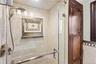 The shower features a handheld showerhead, a tiled niche with decorative accents.