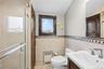 Bathroom featuring a glass-enclosed shower, a vanity with a white sink, and tiled walls with a decorative border