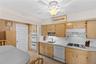 The kitchen features light wood cabinetry, white countertops, and a ceiling fan with integrated lighting