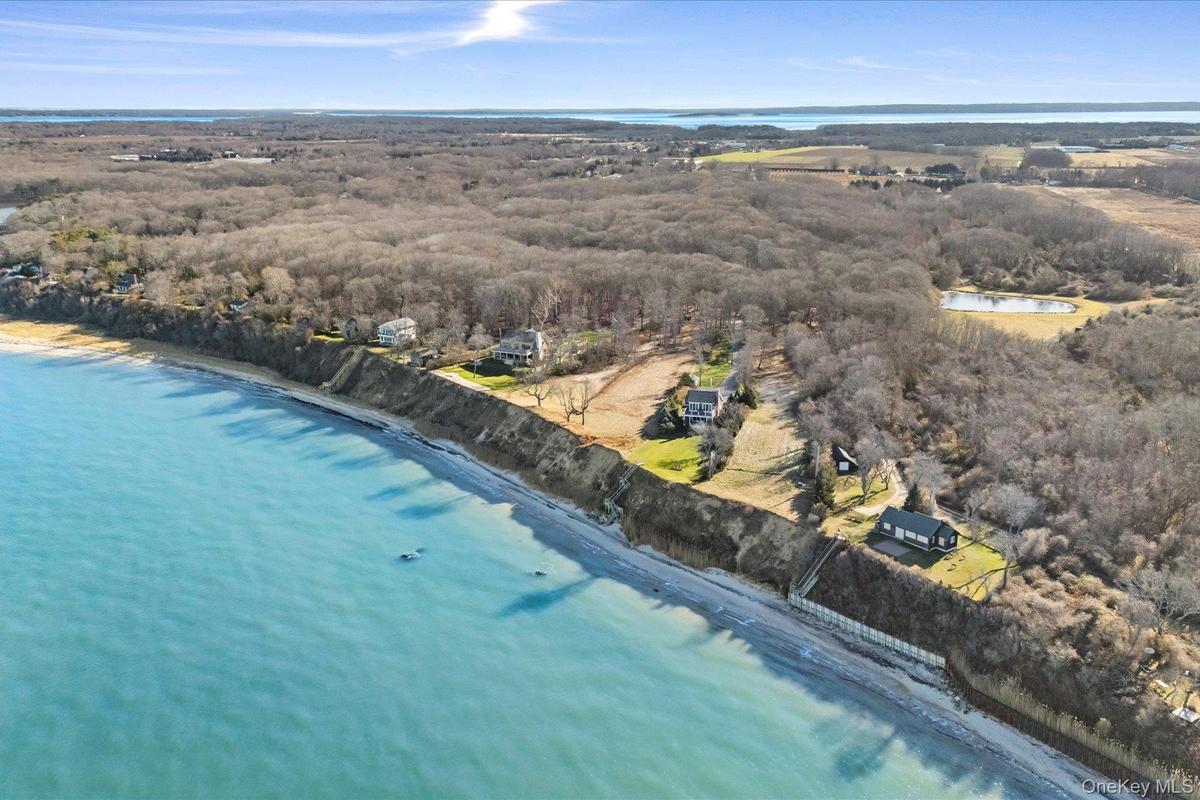 Elevated aerial showcasing a dramatic waterfront land parcel along the bluff, with expansive shoreline views, neighboring properties, and miles of sce
