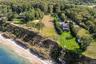 Aerial view highlighting the property's prime waterfront position along the bluff, with expansive shoreline frontage, open lawn areas, and scenic surr