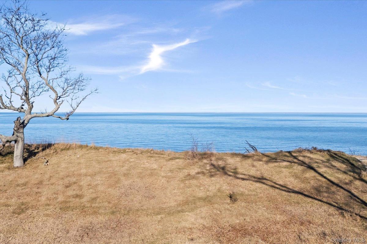 Peaceful bluff-top setting with open lawn and expansive water views, showcasing the property's scenic waterfront backdrop and wide horizon beyond.