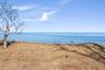Peaceful bluff-top setting with open lawn and expansive water views, showcasing the property's scenic waterfront backdrop and wide horizon beyond.