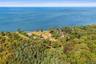 High aerial view showcasing the property's exceptional proximity to the waterfront, surrounded by mature trees and neighboring properties, with expans