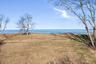 Expansive open lawn on the bluff with unobstructed water views, framed by mature trees and wide blue-sky horizons along the shoreline.