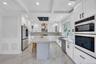 Kitchen with a breakfast bar, a sink, beamed ceiling, wall chimney exhaust hood, and appliances with stainless steel finishes