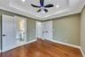 Unfurnished bedroom with wood finished floors, connected bathroom, a raised ceiling, baseboards, and ornamental molding