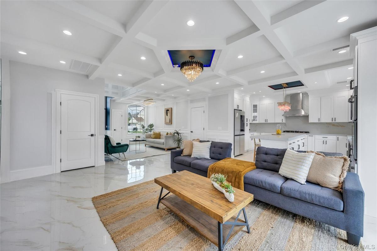 Living room with beamed ceiling, an inviting chandelier, marble finish floor, and coffered ceiling