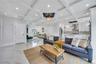 Living room with beamed ceiling, an inviting chandelier, marble finish floor, and coffered ceiling