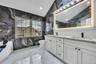 Bathroom with a sink, double vanity, toilet, tile walls, and marble finish floor