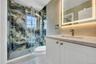 Bathroom featuring toilet, vanity, and a marble finish shower