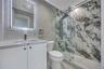 Full bathroom featuring tile walls, toilet, vanity, and a marble finish shower