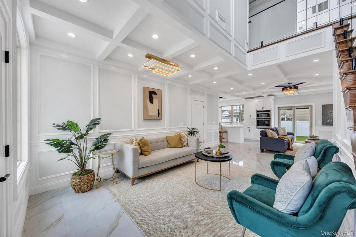 Living room featuring beam ceiling, recessed lighting, coffered ceiling, marble finish floor, and a decorative wall