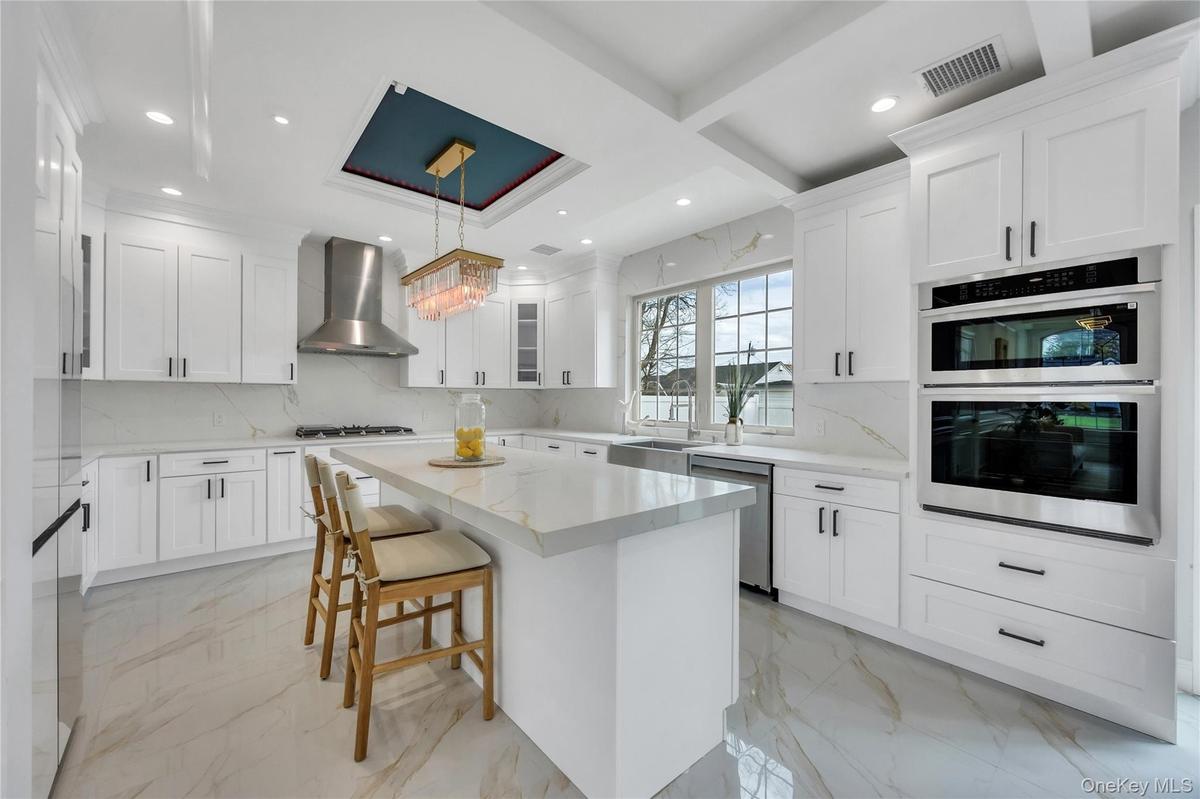 Kitchen with wall chimney exhaust hood, marble finish floor, stainless steel appliances, and visible vents