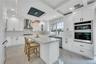 Kitchen with wall chimney exhaust hood, marble finish floor, stainless steel appliances, and visible vents