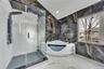 Full bathroom with a shower stall, marble finish floor, a freestanding tub, and stone wall
