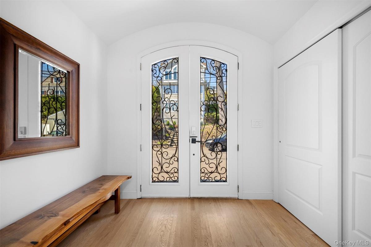 The property features a bright entryway with light wood flooring, double arched doors and white walls