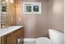 This bathroom features a contemporary vanity with a white countertop and a vessel sink, a decorative mirror backsplash, and a white toilet
