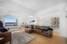 This spacious living area features hardwood floors, white walls, and a large arched window offering expansive water views