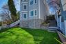 The property features a well-maintained lawn, a stone facade, and multi-level outdoor stairs.