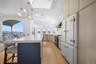 The kitchen features a spacious island with a white countertop and seating, hardwood floors, and large windows with water views