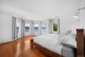 This room features hardwood floors and a white color palette, complemented by a series of bay windows providing expansive water views
