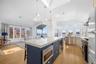 The kitchen features a large island with a white countertop and blue cabinetry, a built-in microwave, and pendant lighting