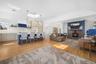 This open-concept living space features hardwood floors, a kitchen island with seating, pendant lighting, and a skylight