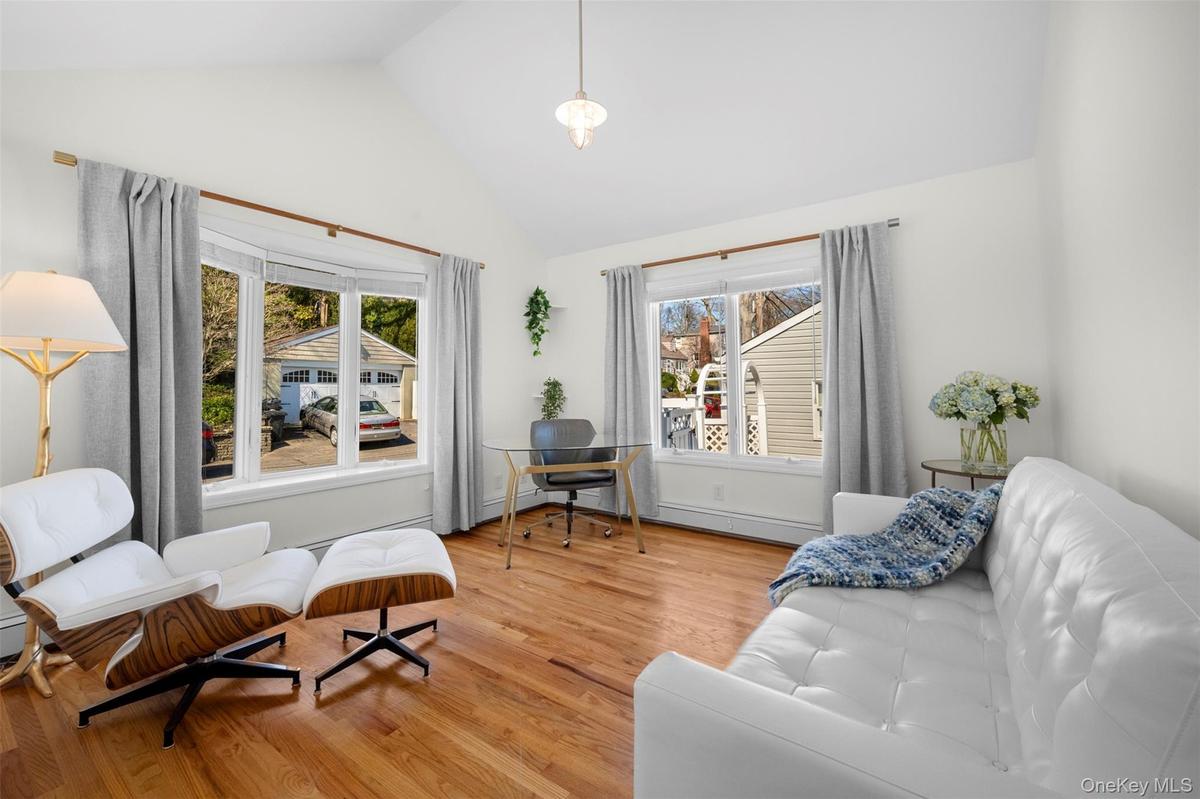 This bright room features hardwood floors, a vaulted ceiling, and ample natural light from multiple windows