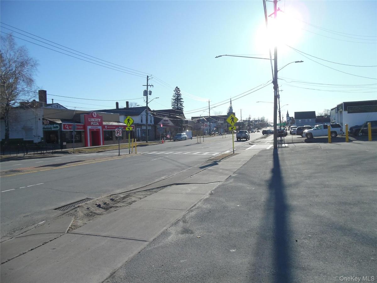 View of asphalt street featuring sidewalks, traffic signs, curbs, and street lights