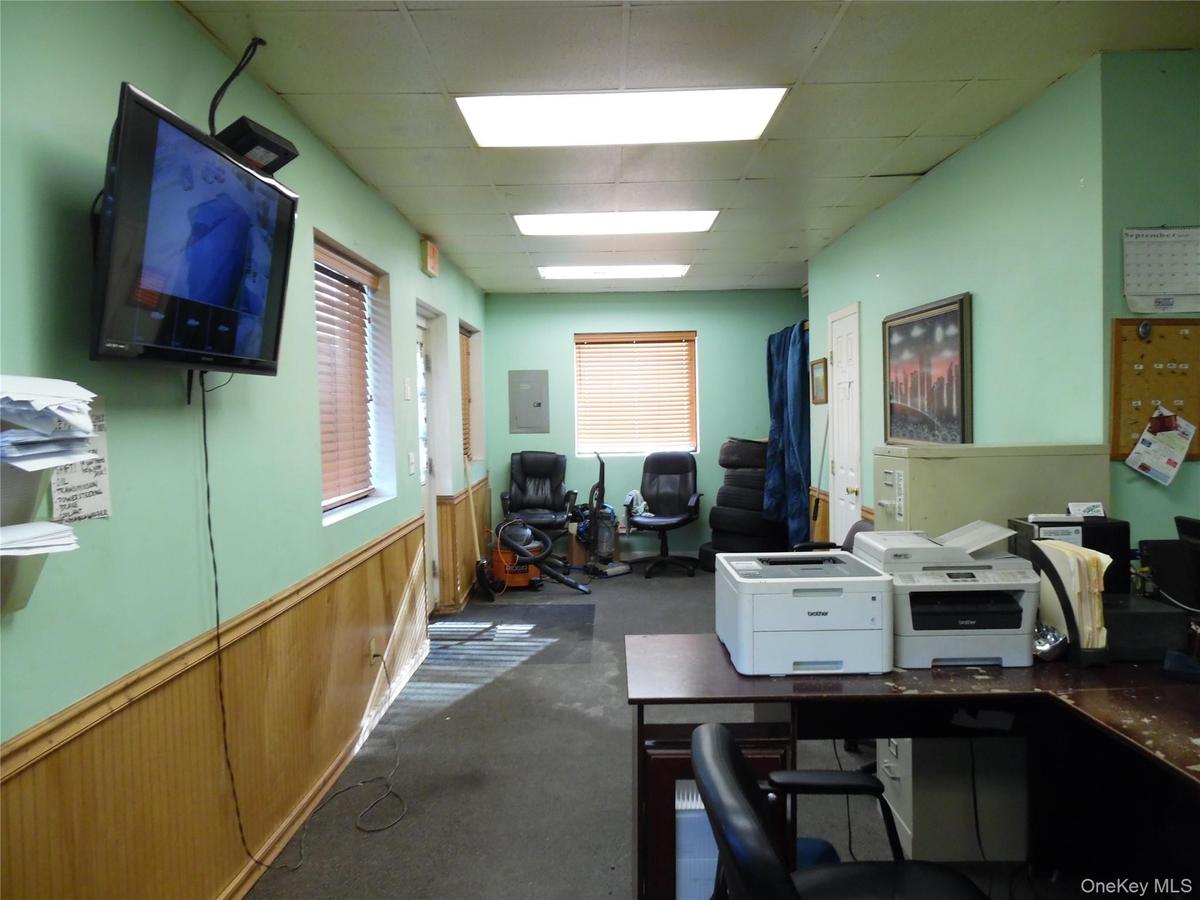 Office featuring a drop ceiling, electric panel, and a wainscoted wall
