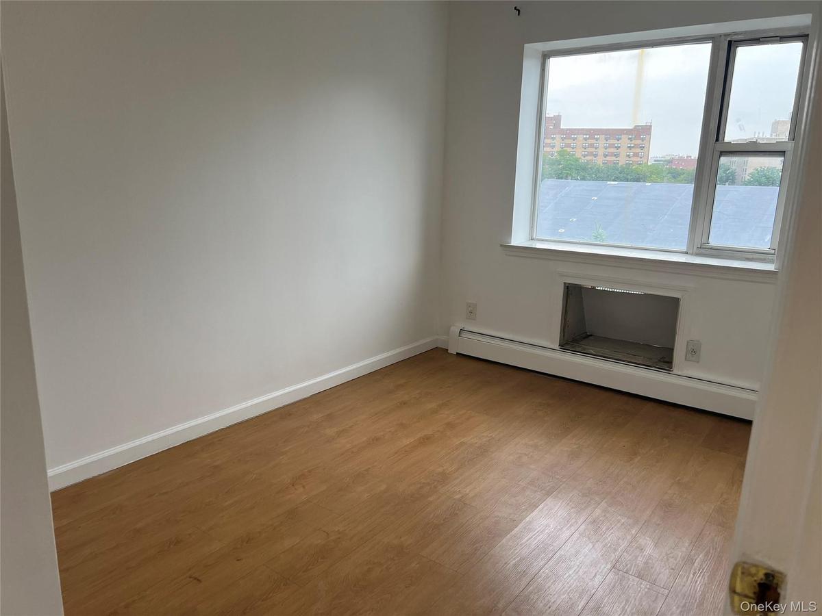 Empty room featuring wood finished floors, baseboard heating, and baseboards