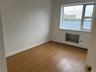 Empty room featuring wood finished floors, baseboard heating, and baseboards