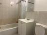 Bathroom with toilet, vanity, shower / bath combo with shower curtain, and tile walls