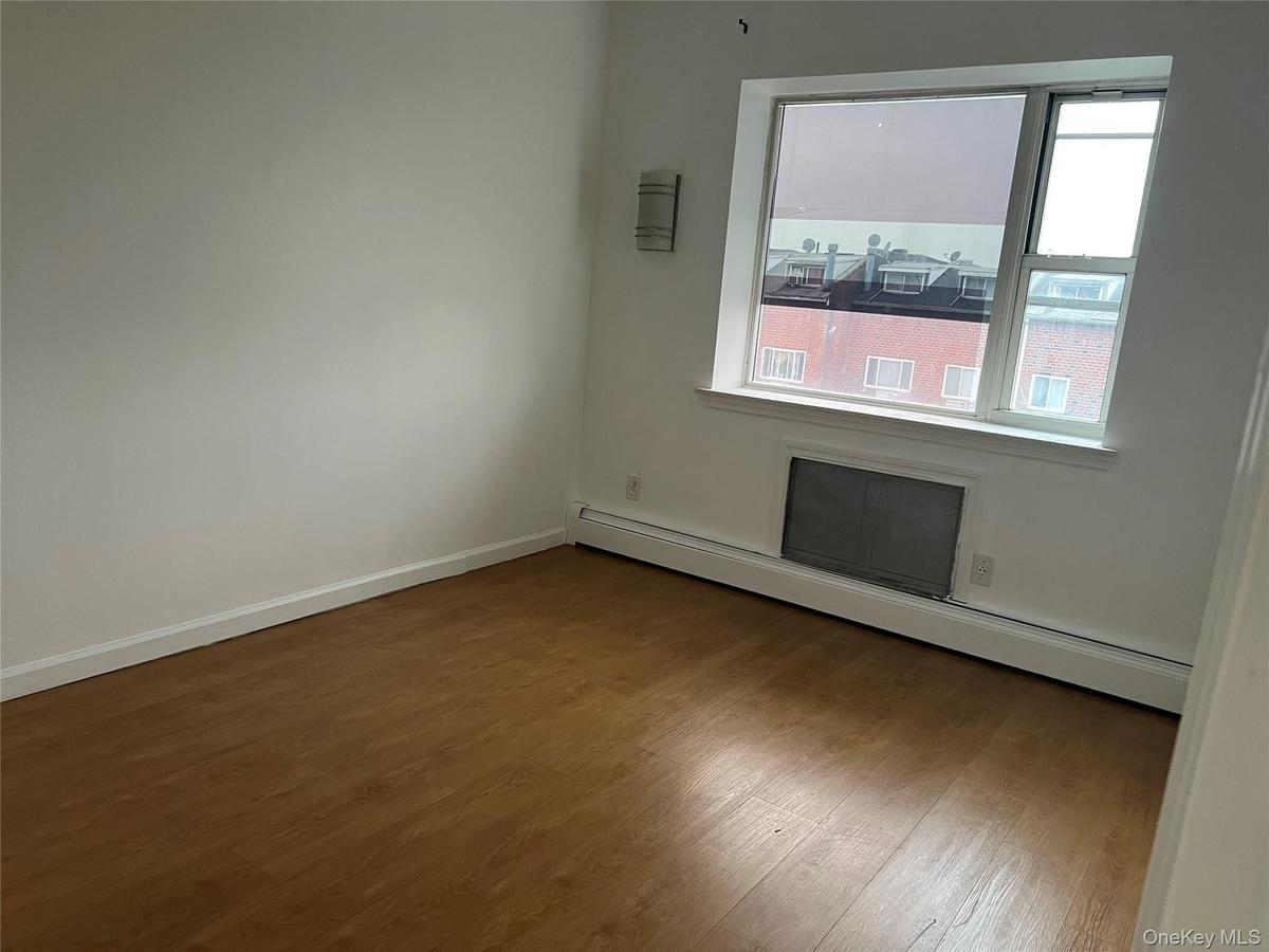 Empty room featuring a baseboard radiator, wood finished floors, and baseboards
