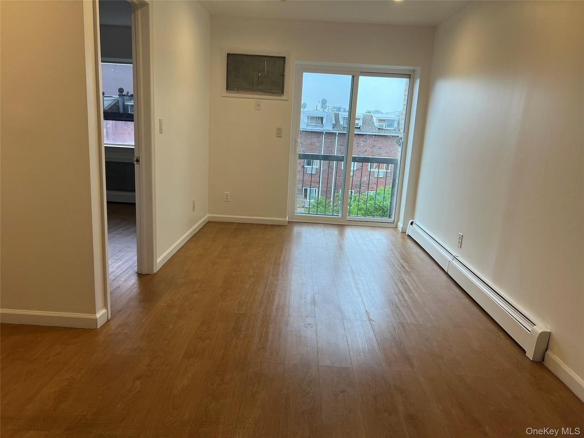 Unfurnished room with a baseboard radiator, plenty of natural light, wood finished floors, and baseboards