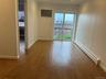 Unfurnished room with a baseboard radiator, plenty of natural light, wood finished floors, and baseboards