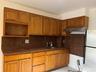Kitchen featuring freestanding refrigerator, ventilation hood, a sink, dark stone counters, and decorative backsplash